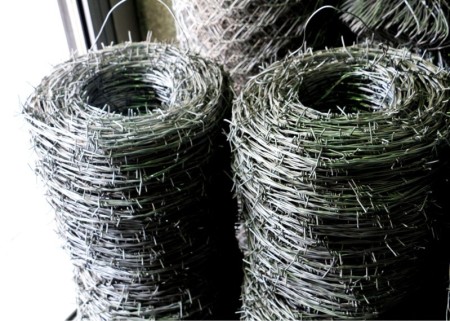 Machine for producing linear barbed wire in two strands